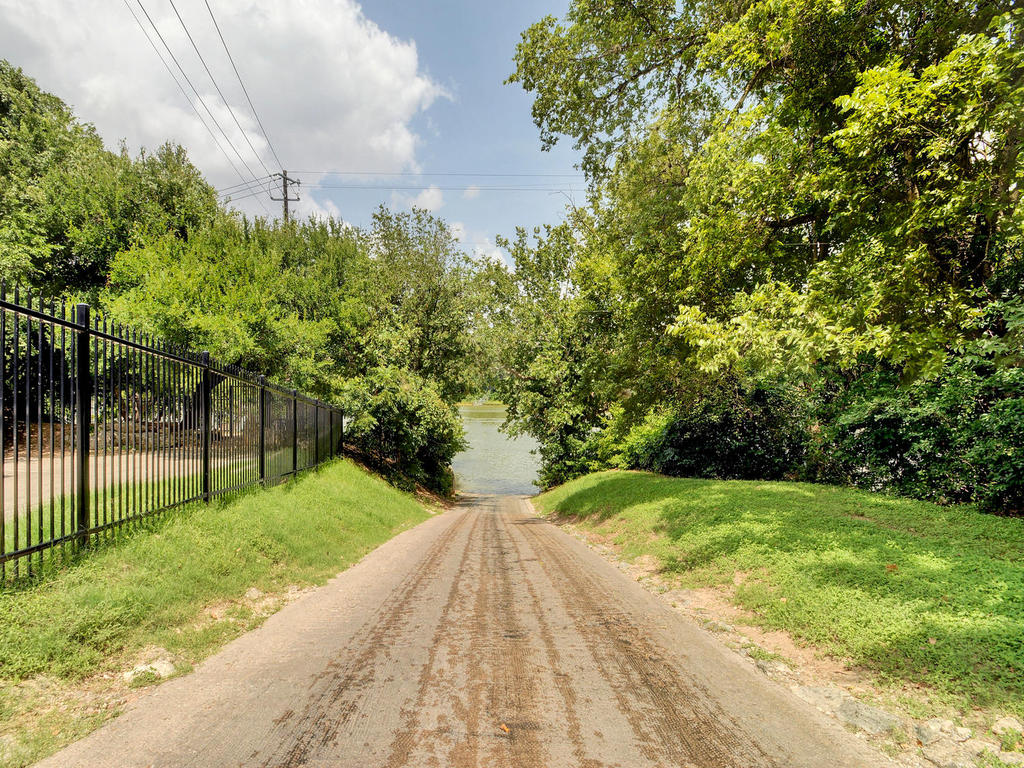 Gated entrance road leading down to the Apache Shores private boat ramp on Lake Austin