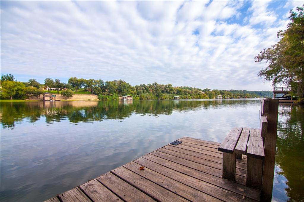 Bench at the end of an Apache Shores dock looking across Lake Austin toward boat docks and tree-lined bluffs